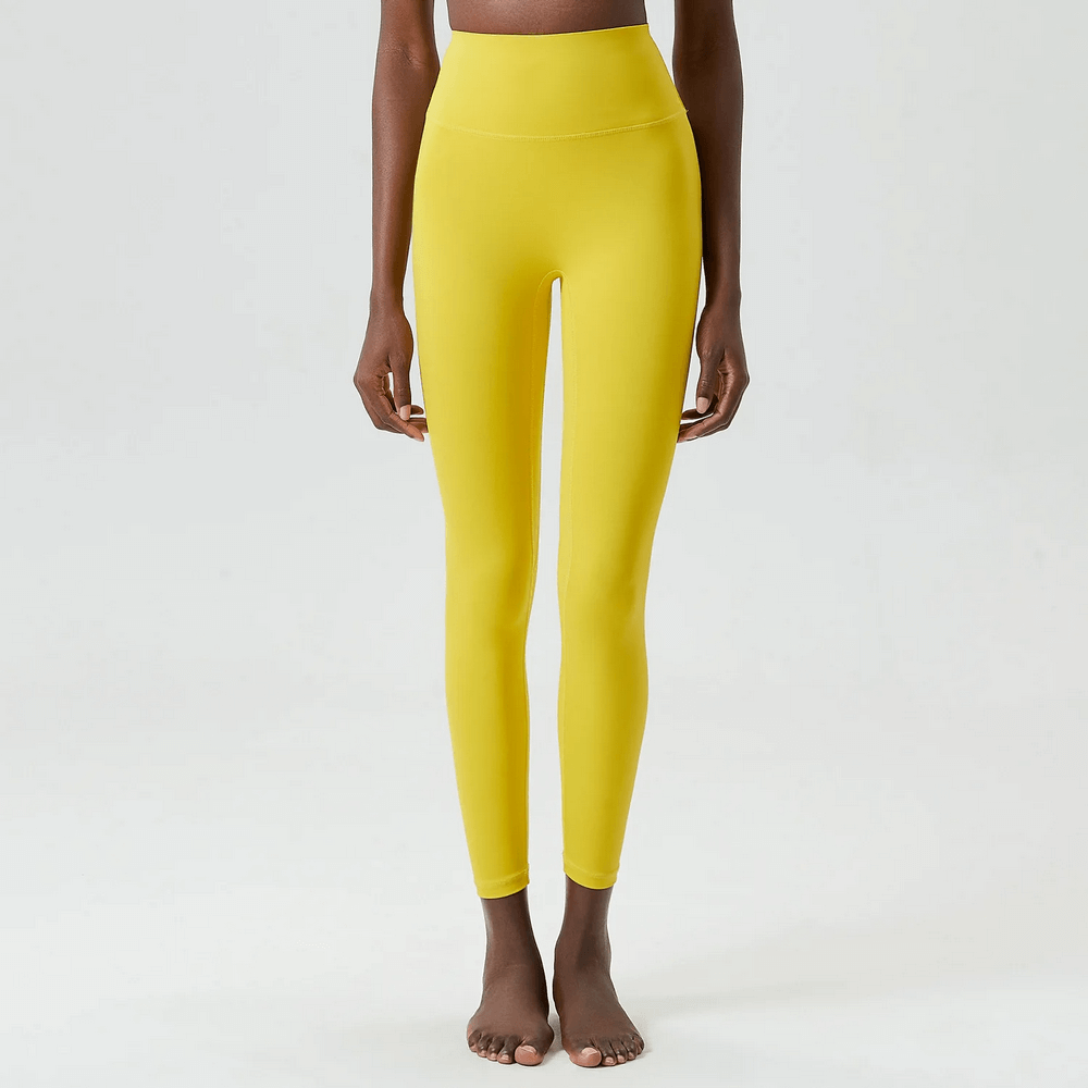 Woman wearing stylish yellow ankle-length yoga leggings, designed for versatile workouts, featuring a durable elastic waist for perfect fit.